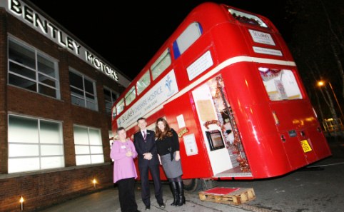 St Luke's deputy matron Gloria Mundie and director Andrea Fragata Ladiara with Bentley Motors' Mike Hawes outside the Santa's Grotto aboard Luke the Bus