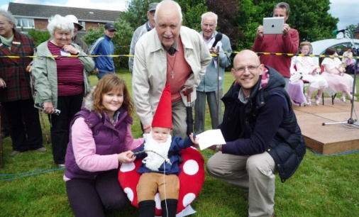 Laurie Clough (standing) presents the prize to fancy dress winner Jack Rhys Chadwick with parents Paul and Hannah Chadwick