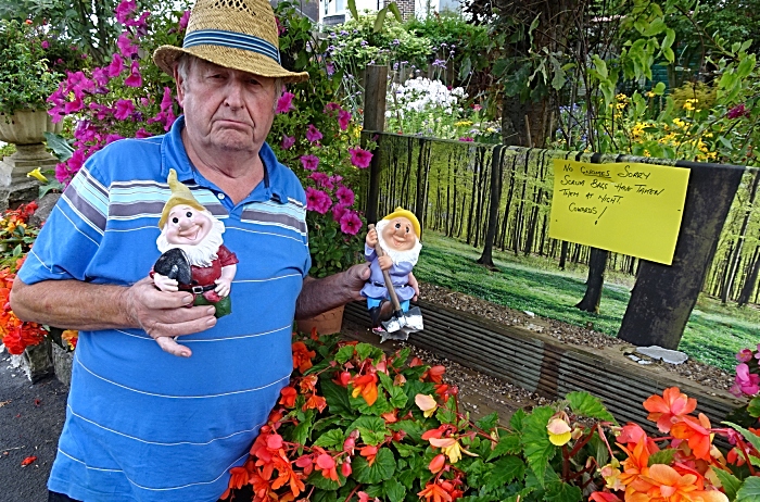 Laurence Perry with two gnomes ripped from their base and the now empty wooden shelf at the front of his garden (1)