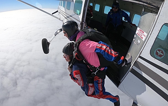 Sarah Iggo exits the plane with instructor for her tandem skydives